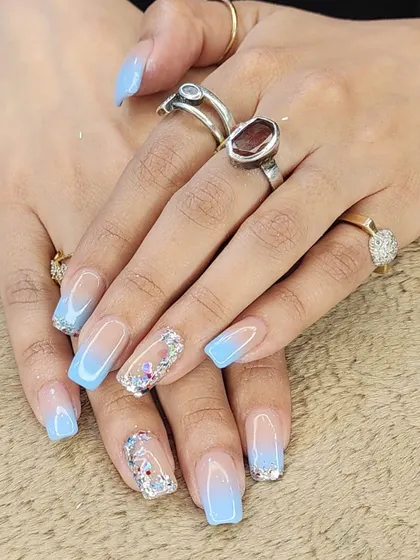 A beautiful "glass" nail effect. This set features a light blue ombre with encapsulated glitter and butterfly sequins, creating a multi-dimensional and sparkling look.