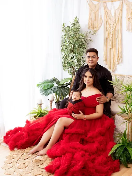 A wide shot of a newborn family session, showcasing the dramatic red gown and lush green backdrop. I provide a variety of setups to match your style.