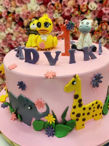A full view of the pink jungle theme cake, showcasing the arrangement of the fondant animals and flowers.