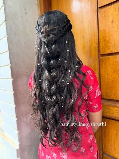 A romantic half-up style with a braided crown, a small bun, and loose waves scattered with pearls. This creates a dreamy, fairytale-like effect, perfect for an engagement or reception.
