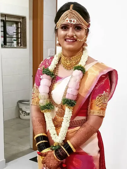 A happy bride ready for her muhurtham. This look features a traditional headpiece (baashinga), heavy jewelry, and a bright, fresh makeup look perfect for a morning ceremony.