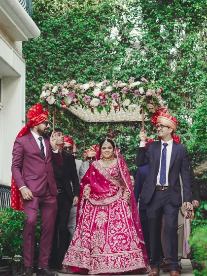 The bride's grand entrance under a beautiful floral phoolon ki chaadar, held by her brothers. A traditional and emotionally charged moment.