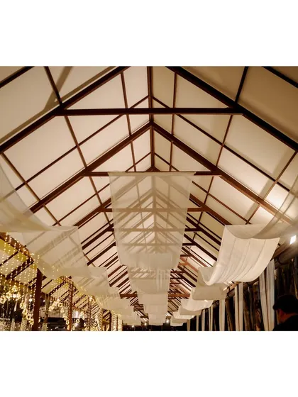 The ceiling of the Sangeet venue is draped with white fabric, creating a soft and elegant canopy for the celebration.