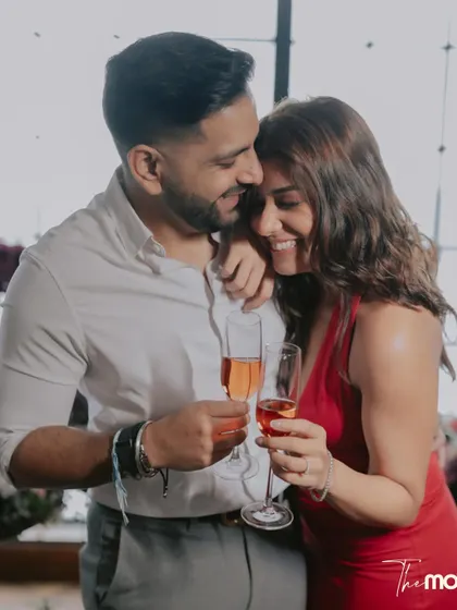 A happy, candid moment with champagne glasses at Soho House Mumbai. The couple's smiles and close embrace perfectly capture the celebratory and romantic mood.