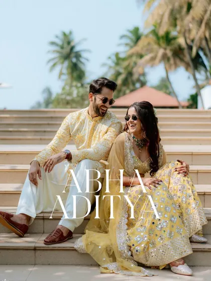 The couple sharing a laugh on the steps of their Goa venue. Their coordinated yellow outfits and sunglasses add a cool, modern vibe.