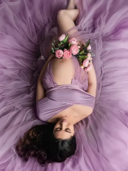 A peaceful moment captured from above. The soft lavender fabric and fresh flowers create a beautiful and artistic composition for this maternity portrait.