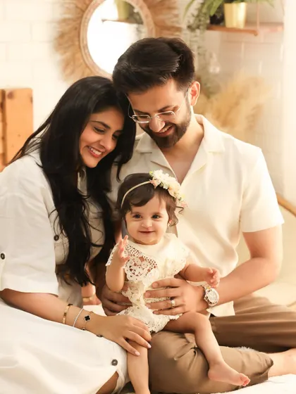 A beautiful family of three in our boho studio. The parents' loving gaze and the baby's happy wave create a portrait that is both heartwarming and picture-perfect.