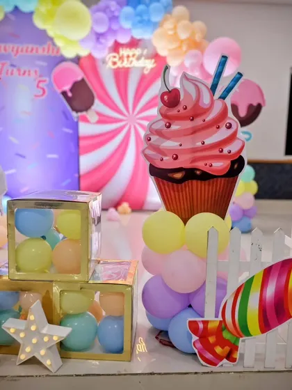 A close-up of the delightful props at Ravyanshi's Candyland party, including a giant cupcake, candy cutouts, and 'BABY' blocks filled with colorful balls.