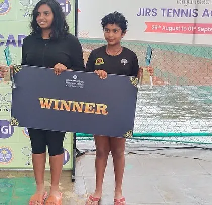 Eshita and her partner holding the "WINNER" board after their doubles victory at the JIRS Tennis Academy.