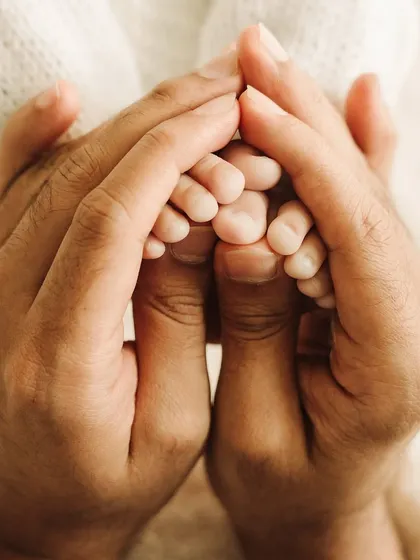 A beautiful macro shot of newborn feet held in their parent's hands, showcasing every tiny wrinkle and perfect toe.