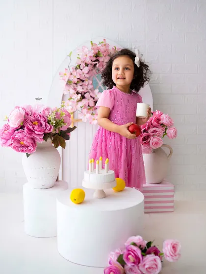 A pink-themed birthday setup for a sweet little girl, complete with a prop cake and beautiful flowers.