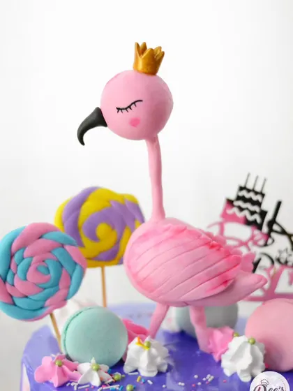 A close-up of the hand-sculpted flamingo topper, complete with a tiny golden crown.