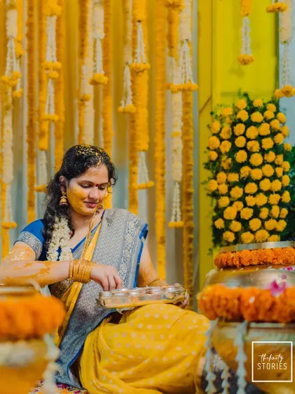 The bride participates in the Haldi rituals, surrounded by beautiful yellow floral decor, a picture of grace and tradition.