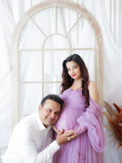 A tender moment between a couple, with the dad-to-be listening to the baby bump. The soft lavender of the gown adds to the dreamy atmosphere.