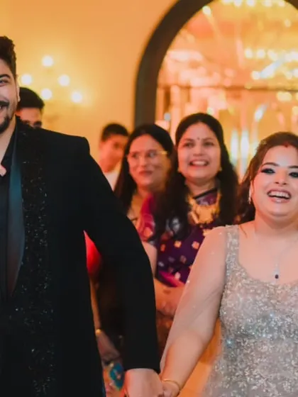 The couple's joyful entrance into their reception, hand in hand, with big smiles for their waiting guests.