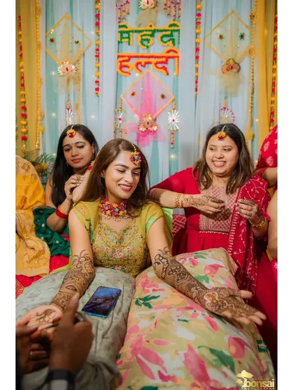 A candid moment of the bride getting her Mehndi done, surrounded by friends.