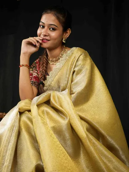 A model in a golden tissue saree wears a matching gold-toned necklace, showing how to create a glamorous, single-color ethnic look.