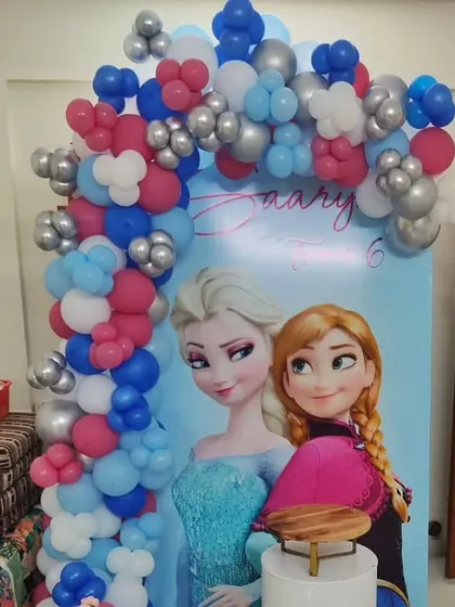 A classic Disney Frozen theme for a 6th birthday. The backdrop features Elsa and Anna, framed by a balloon arch in signature icy blue, pink, and silver colors.