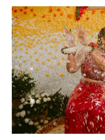 A close-up of a bride during a ritual bath, capturing the water splashing and her happy expression.