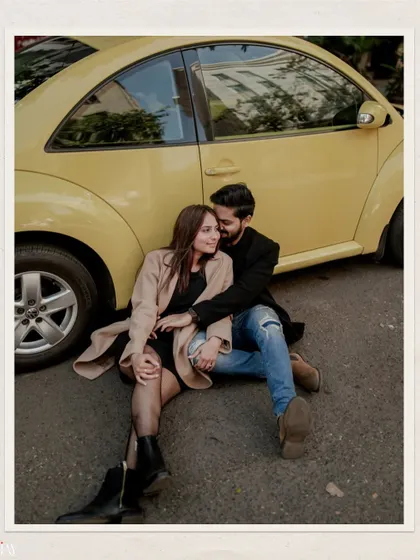 An intimate and relaxed photo of the couple sitting by the yellow car, capturing a quiet moment.