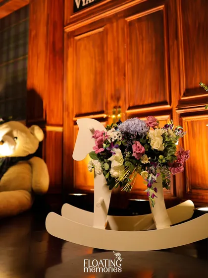 A classic rocking horse, adorned with a beautiful floral arrangement, sits beside the main stage. This thoughtful detail adds a touch of nostalgia and charm, perfectly complementing the sophisticated teddy bear theme.