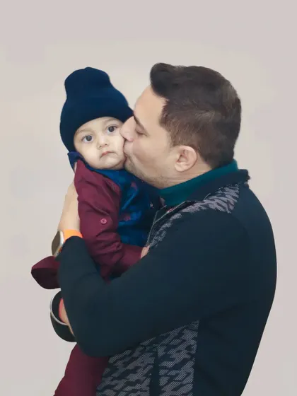 A tender moment as a father gives his son a gentle kiss on the cheek.