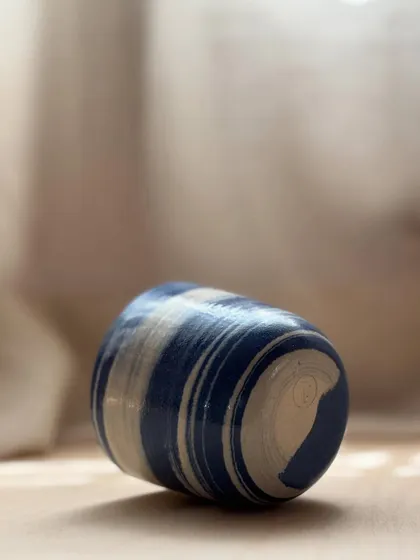 A Blue Fish Tumbler on its side, showing the beautiful swirls of the marbled clay. Each one is like a small, abstract painting.