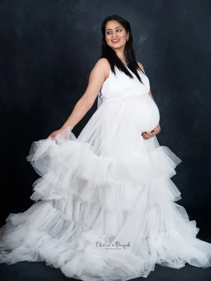A simple and happy portrait in a white ruffled gown. The dark background makes the dress appear even more bright and angelic.