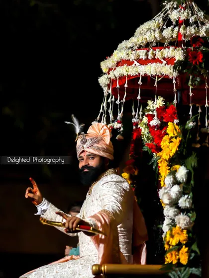 The groom makes a grand entrance, seated in a beautifully decorated Palki. The dramatic lighting highlights his regal attire and celebratory mood.