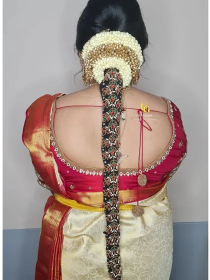 A detailed look at the traditional South Indian hairstyle for Akshatha's muhurtham, featuring a long braid adorned with jasmine and an embroidered 'jadai'.