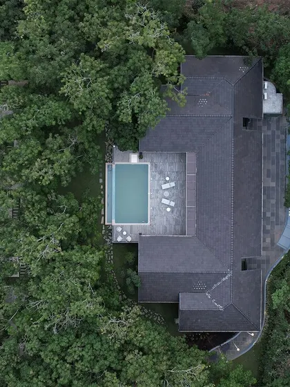 Aerial top-down views of The Leaf Poomala, revealing the U-shaped plan that wraps around a central pool and deck, creating a private sanctuary for guests.