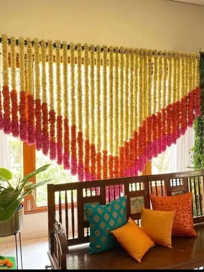A simple and beautiful decoration for a pooja or small ceremony at home. A curtain of marigold and tuberose strings hangs behind a traditional wooden swing, creating a perfect sacred corner.