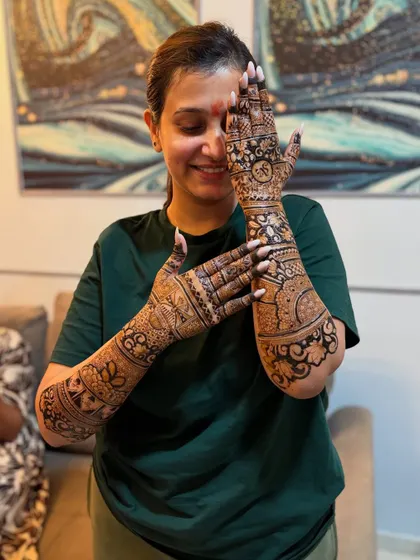 A shy smile from a happy bride. Her joy is evident as she shows off her intricate bridal mehendi.