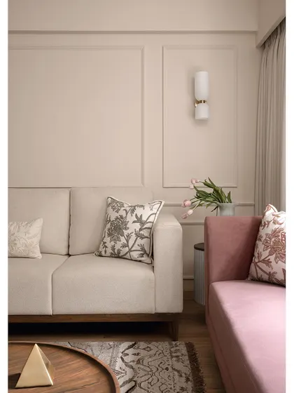 The living room of "Apartment 222" uses a soft, neutral palette to create a calming atmosphere. The pink sofa adds a gentle touch of color, while the embroidered cushions and wall sconces provide layers of detail and warmth.