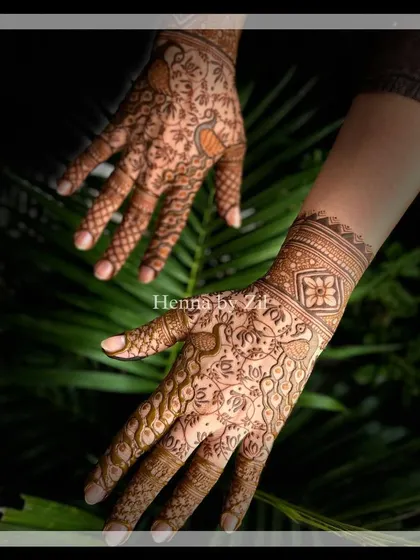 An elegant bridal design with a mix of bold and delicate elements. The wrist cuff features a band of flowers, while the palm is adorned with a flowing pattern of vines and peacocks.