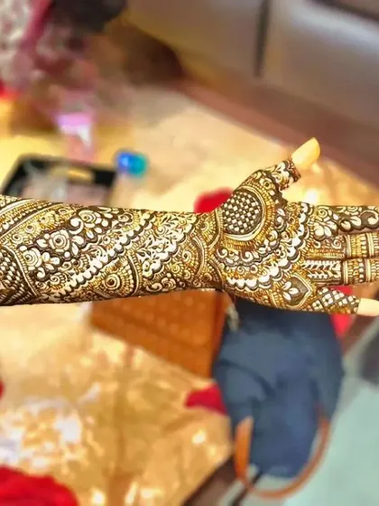 A full-arm bridal design captured in natural light. The pattern features bands of different traditional motifs, creating a rich tapestry of henna art.