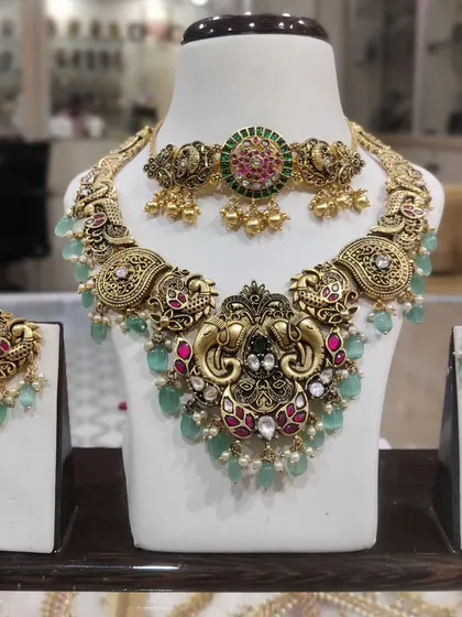 An elegant elephant-motif choker and necklace set with pastel green bead drops. This is a unique take on traditional temple jewellery.