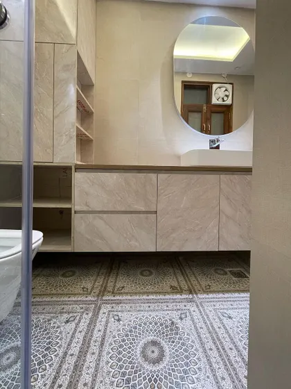 This shot showcases the intricate pattern of the floor tiles, which bring a touch of traditional design into this otherwise modern bathroom. The round mirror adds a soft, contemporary touch.