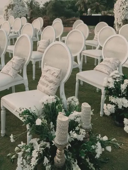 The elegant all-white seating arrangement for the sundowner wedding, with the aisle lined with beautiful white floral arrangements.