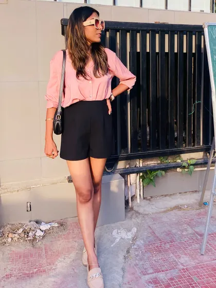 Another pose in the pink shirt and black shorts outfit. I focus on finding pieces that are not just trendy but also practical for my clients' lifestyles.