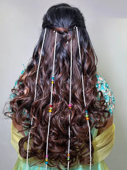 A fun and creative hairstyle for a carnival event, with long curls and beaded pearl strands.