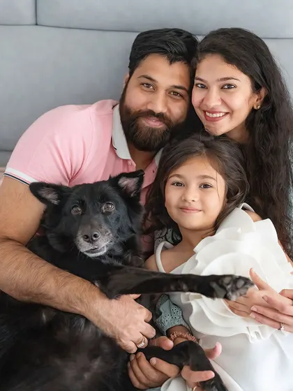A happy family portrait, with their indie dog Pakodi holding up a paw as if to wave.