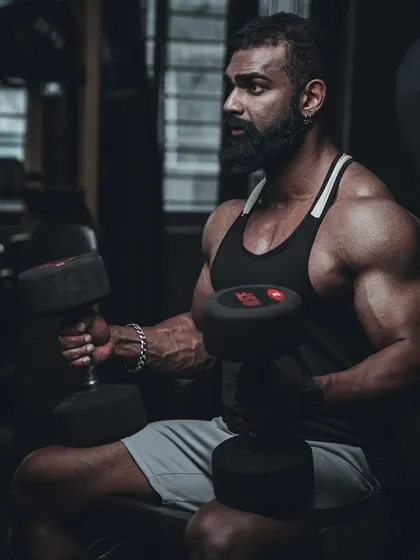 Performing seated dumbbell curls. This is a fundamental exercise for building bicep mass. Don't just wish for it, work for it.