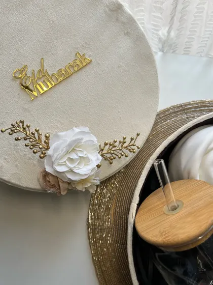 An open view of the velvet Eid box, revealing a glass tumbler and a rolled scarf inside.
