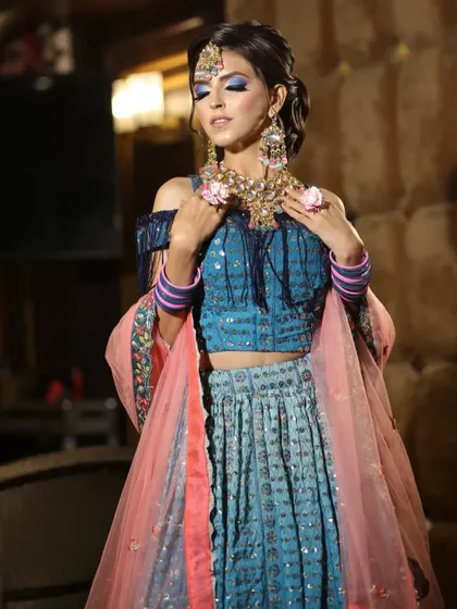 This blue and pink lehenga with an off-shoulder fringed blouse is a trendy and playful choice for a mehendi or sangeet function.