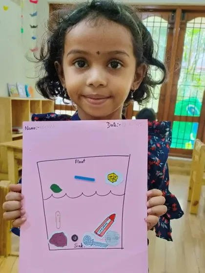 A young girl holds up her float and sink worksheet. We use a mix of hands-on experiments and follow-up activities to ensure concepts are well understood.