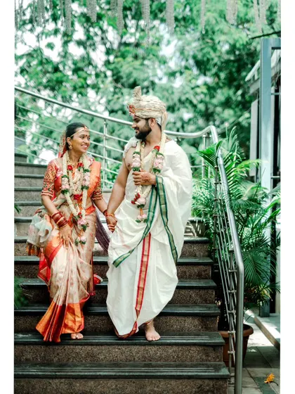 A happy shot of a newly married couple descending a staircase, hand in hand, surrounded by greenery.