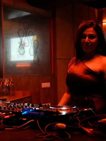 In the zone behind the decks, surrounded by the warm, ambient lighting of the club. This is my space, where I craft the musical journey for the night.