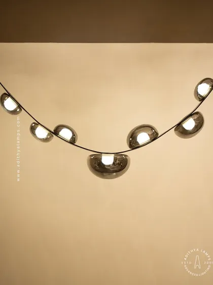 An unconventional design where smoked glass ovals are cradled by a flexible black leather strap. This fixture combines hard and soft textures for a uniquely modern and minimal aesthetic, perfect for creating a talking point in any room.
