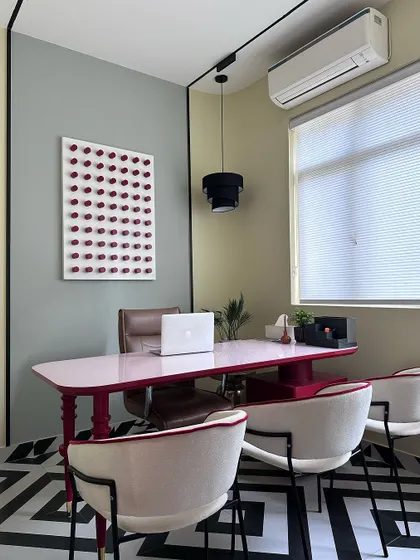 Our principal designer's cabin, showcasing a bold and eclectic style with a custom pink-lacquered desk, geometric flooring, and unique art pieces.